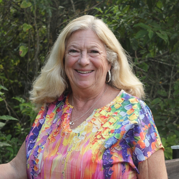 Robin Parker, Kaleidoscope Adventures team member, smiling outdoors in a colorful blouse.