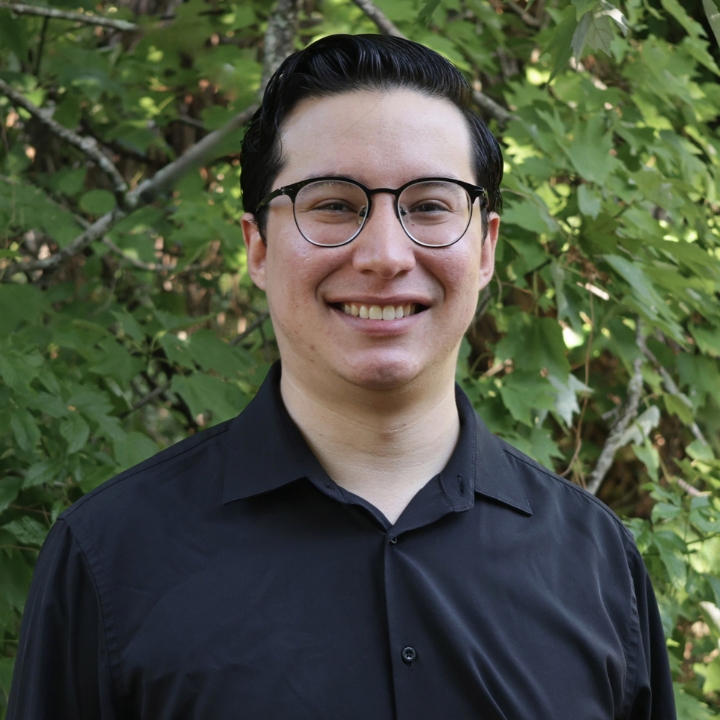 Alex Quintana, Kaleidoscope Adventures team member, smiling outdoors in glasses and a black collared shirt.