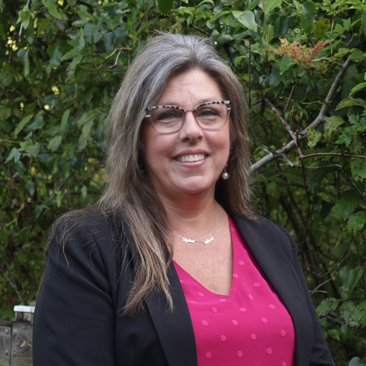 Lisa Scalzo, Kaleidoscope Adventures team member, smiling outdoors in glasses, a black blazer, and a bright pink top.