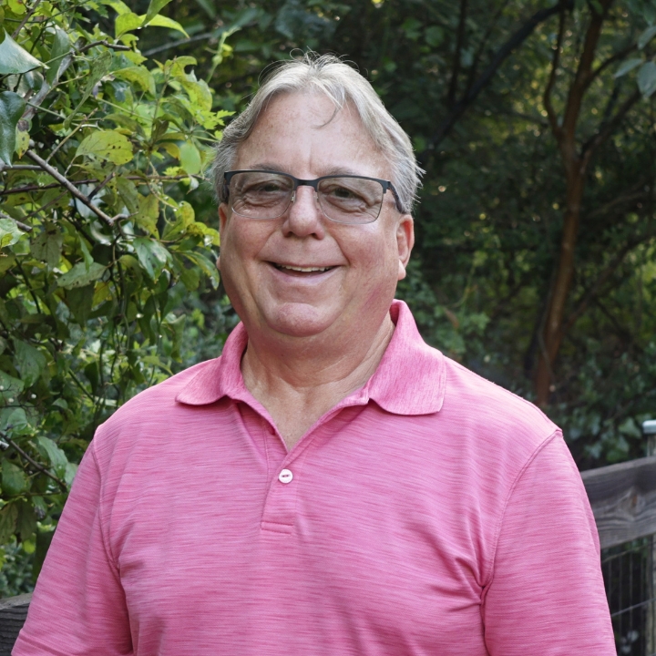 Dave Driscoll, Kaleidoscope Adventures team member, smiling outdoors in glasses and a pink polo shirt.