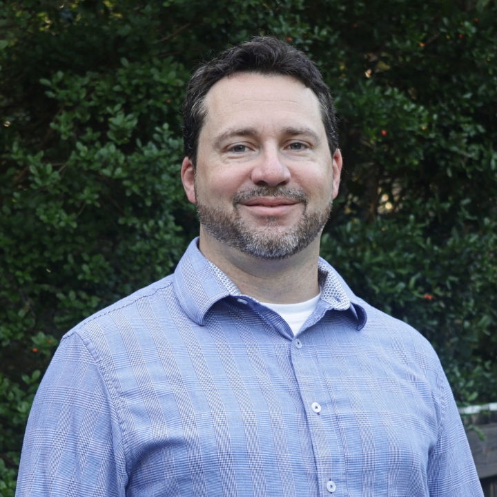 Andrew Haderthauer, Kaleidoscope Adventures team member, smiling outdoors in a blue collared shirt.