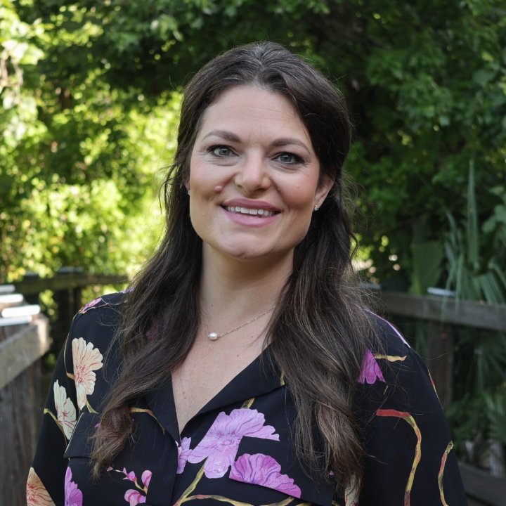 Kacey Constantino, Kaleidoscope Adventures team member, smiling outdoors in a black floral blouse.