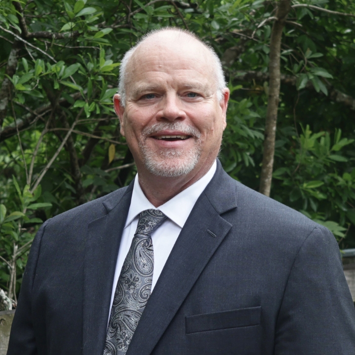 Steven Moore, Kaleidoscope Adventures team member, smiling outdoors in a dark suit and patterned tie.