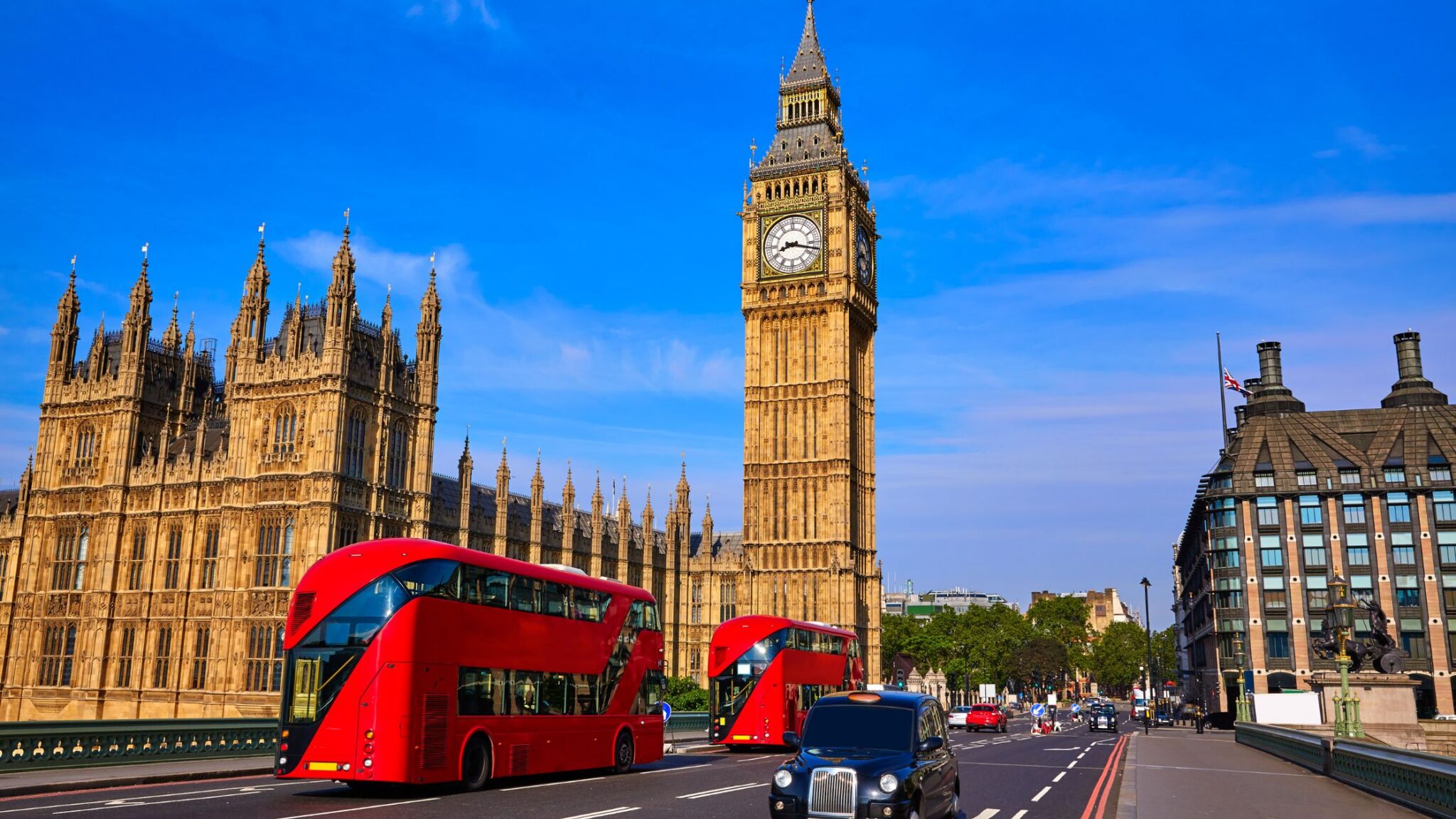 image of Big Ben and Buckingham Palace with red double-decker buses in the foreground and deep blue sky in the background