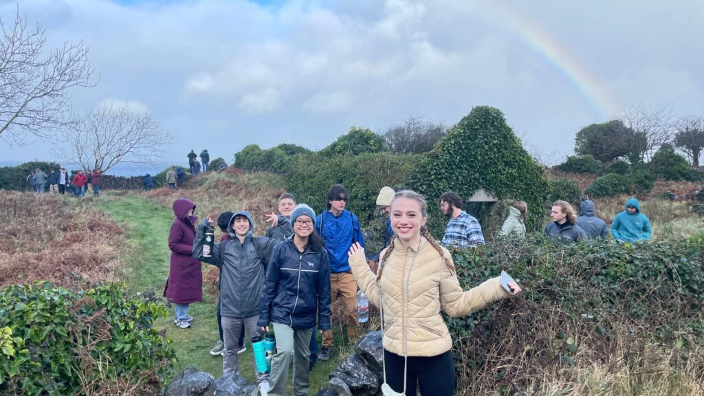 group of high school students exploring an outdoor historic site in Ireland with a rainbow in the background