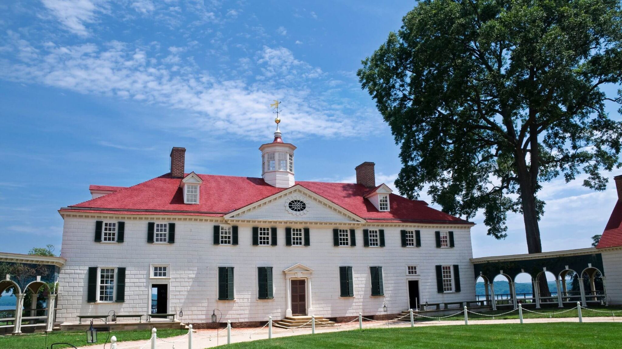 large white mansion with a red roof set against a deep blue sky