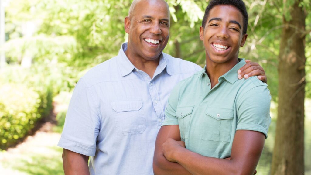 African-American father and son facing the camera and smiling for a photo