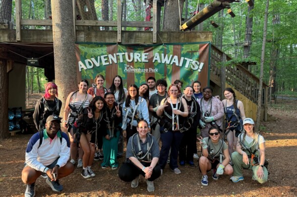 Everything Teachers and Directors Want to Know to Plan a Great Trip group of older teens and adults posing for a photo in a wooded setting in front of a sign that reads