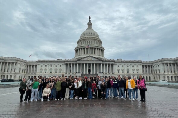 large group of students and teachers posing for a picture in front of the capitol building