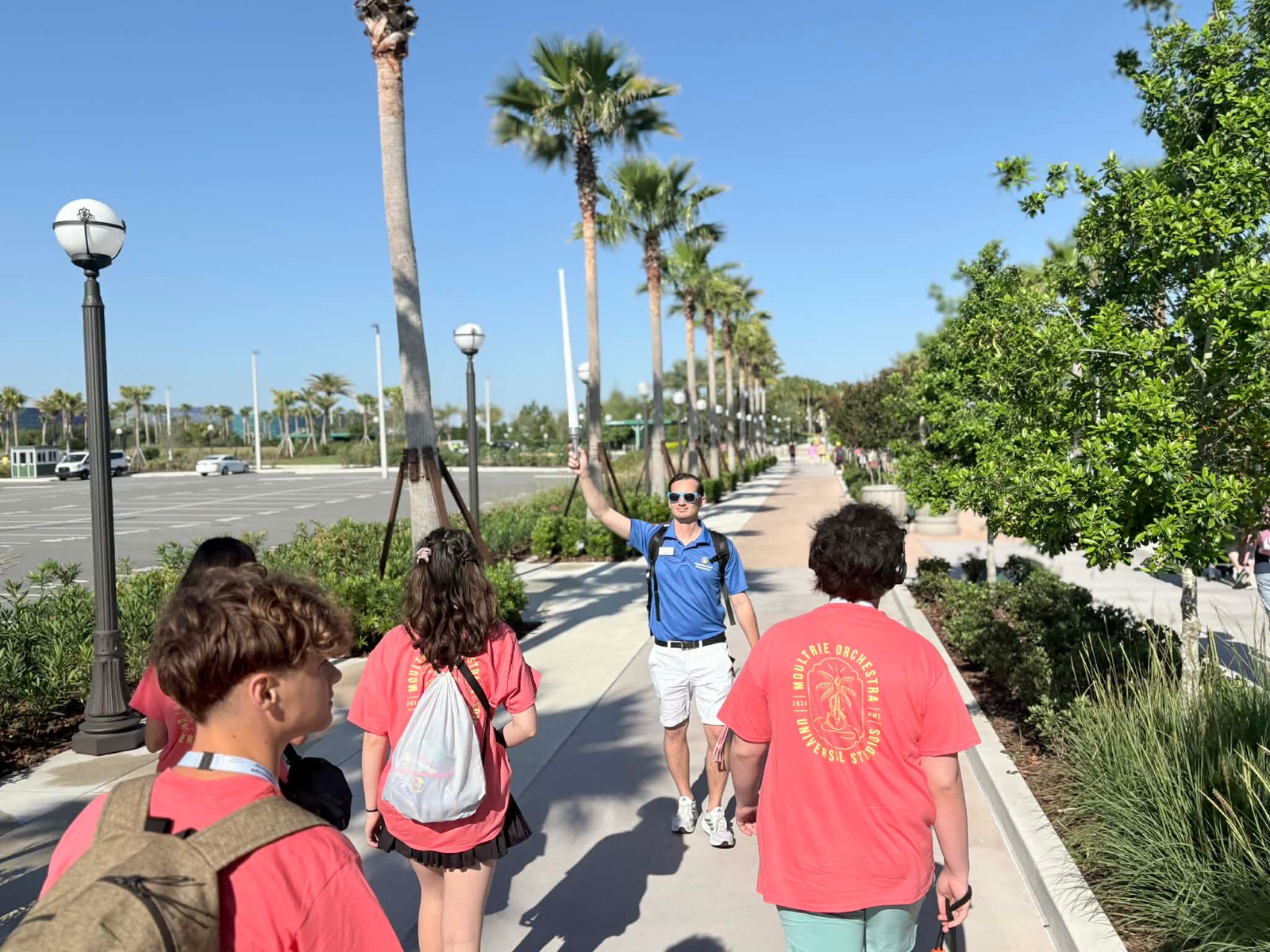 tour director leading a group of young teens into a park setting