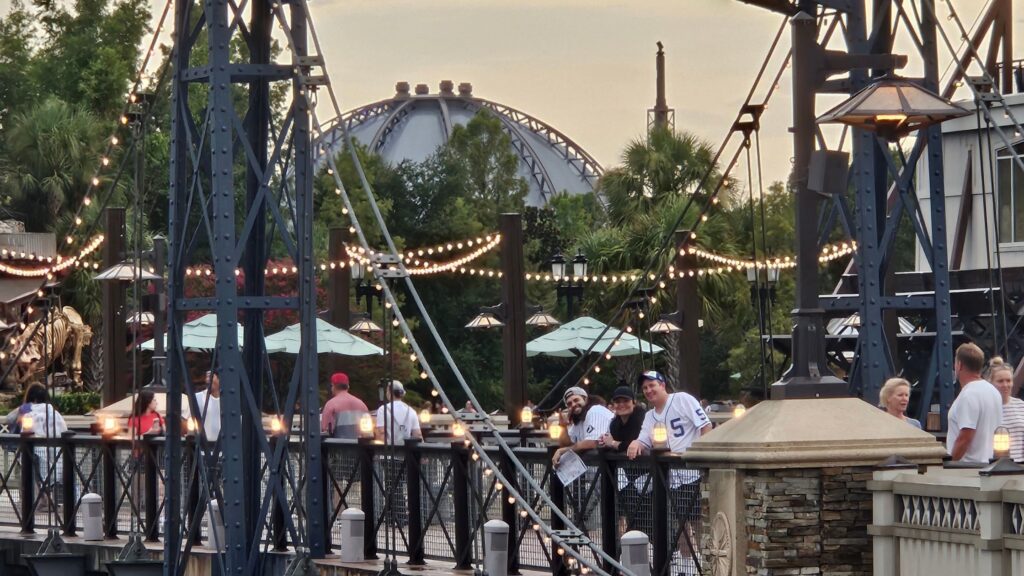 A crowd crossing a brightly lit bridge in Disney Springs