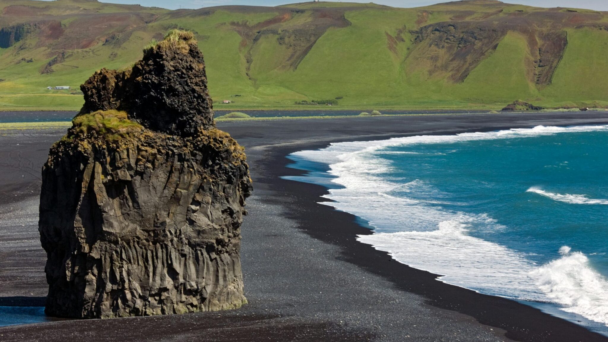 Iceland black sand beach contrasts with deep blue water and green mountains
