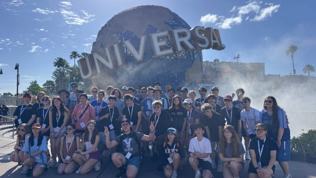 large group of teens posing in front of the Universal globe