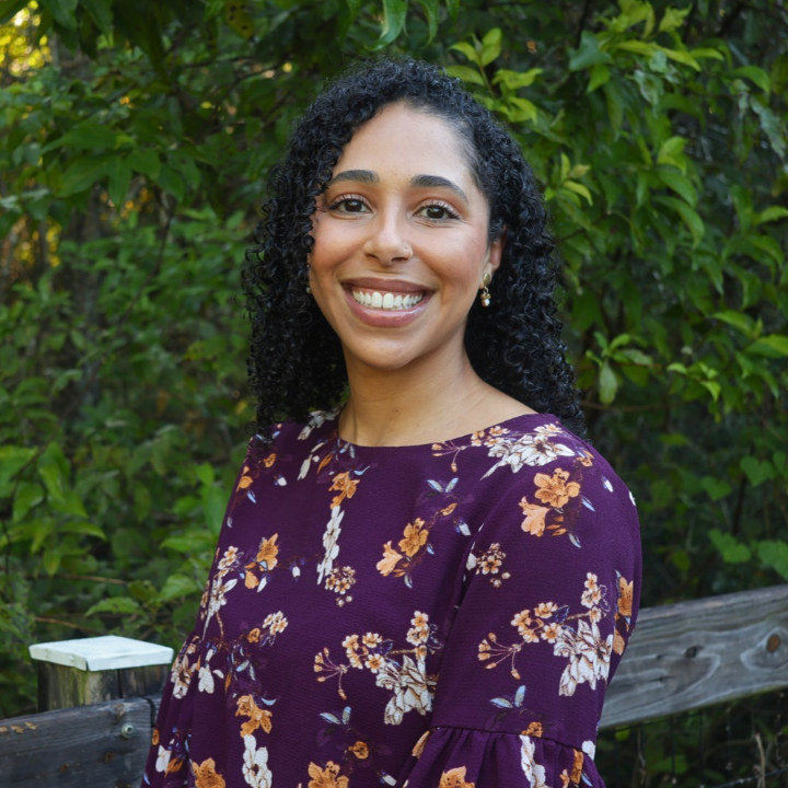 Lauren Shahan, Kaleidoscope Adventures team member, smiling outdoors in a purple top that has a floral design.