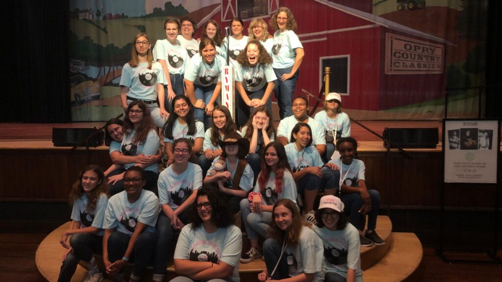 large group of teen girls posing in front of a red barn