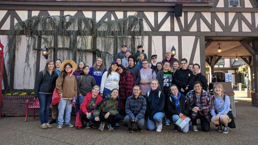 large group of teens posing in front of a Tudor style wall